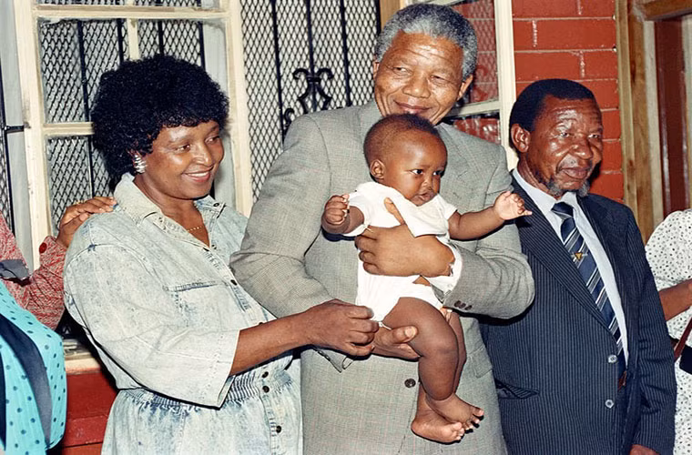 Vợ chồng cựu Tổng thống Mandela chơi đùa với cháu, Bambata, tại nhà ở Soweto năm 1990. Ảnh: Getty.