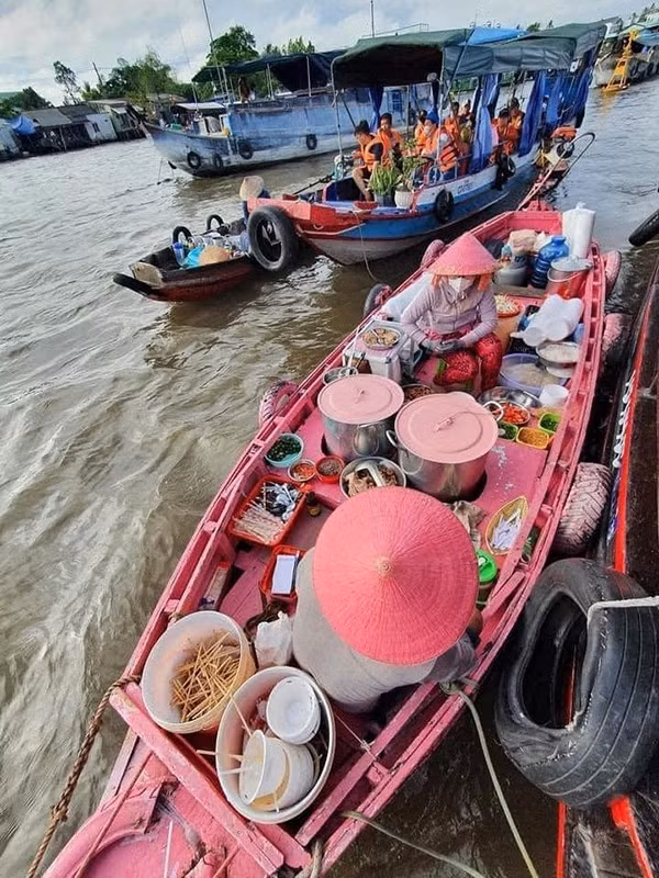 Khác với những chiếc ghe thông thường, chiếc ghe bún riêu này ở chợ nổi Cái Răng được sơn màu hồng bắt mắt, ngồi bên trong là cô bán bún với chiếc nón lá màu hồng dễ thương không kém. Ảnh: Phạm Đỗ Minh Trung