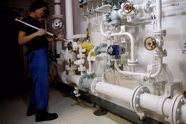 Nữ thủy thủ Nhật Bản này đang lau sạch các ống bên trong khu vực hành lang của tàu Kaga.