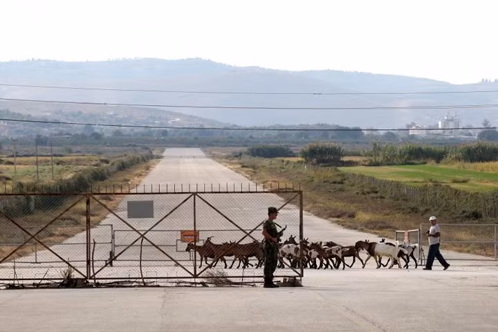 Một người chăn cừu đang dẫn bầy cừu đi ngang qua căn cứ không quân Kucova.