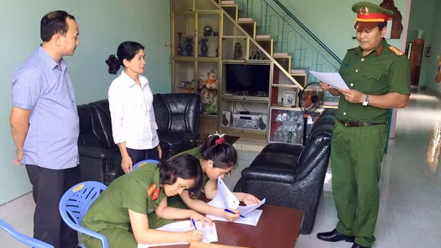 Công an đọc lệnh bắt giữ bà Lê Thị Hồng Loan (54 tuổi, áo trắng) - kế toán trưởng Ngân hàng Agribank chi nhánh huyện Krông Bông, Đắk Lắk vào ngày 6/10 - Ảnh: CA cung cấp