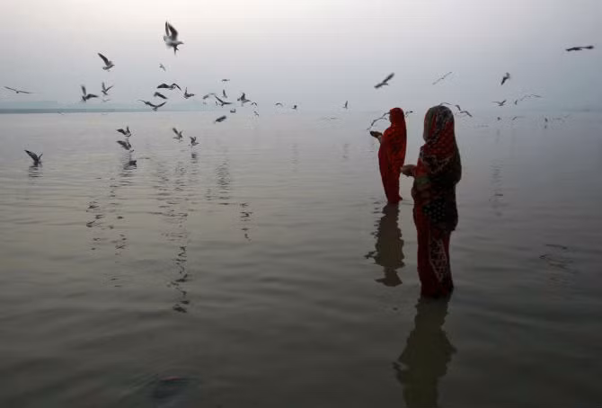 Hai phụ nữ theo đạo Hindu cầu nguyện ở sông Ganga, Allahabad, Ấn Độ, khi họ chờ Mặt trời mọc.