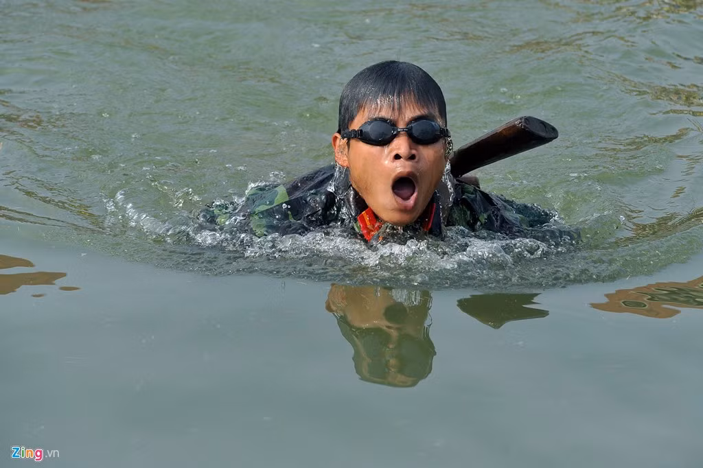 Người lính trổ tài bơi với súng AK, một trong những nội dung huấn luyện hải quân đánh bộ (thủy quân lục chiến) - lực lượng tinh nhuệ của Hải quân nhân dân Việt Nam. Một người lính hải quân đánh bộ phải giỏi nhiều kỹ năng: sử dụng thành thạo các loại vũ khí trang bị, bơi giỏi, chịu được sóng gió (có thể lên đến cấp 6), am hiểu thời tiết biển, thể lực tốt. Khi đổ bộ vào bờ, hải quân đánh bộ phải tác chiến ngay. Họ chiến đấu như bộ binh và kỹ năng chiến đấu phải cao hơn bộ binh. Ảnh: Zingnews.