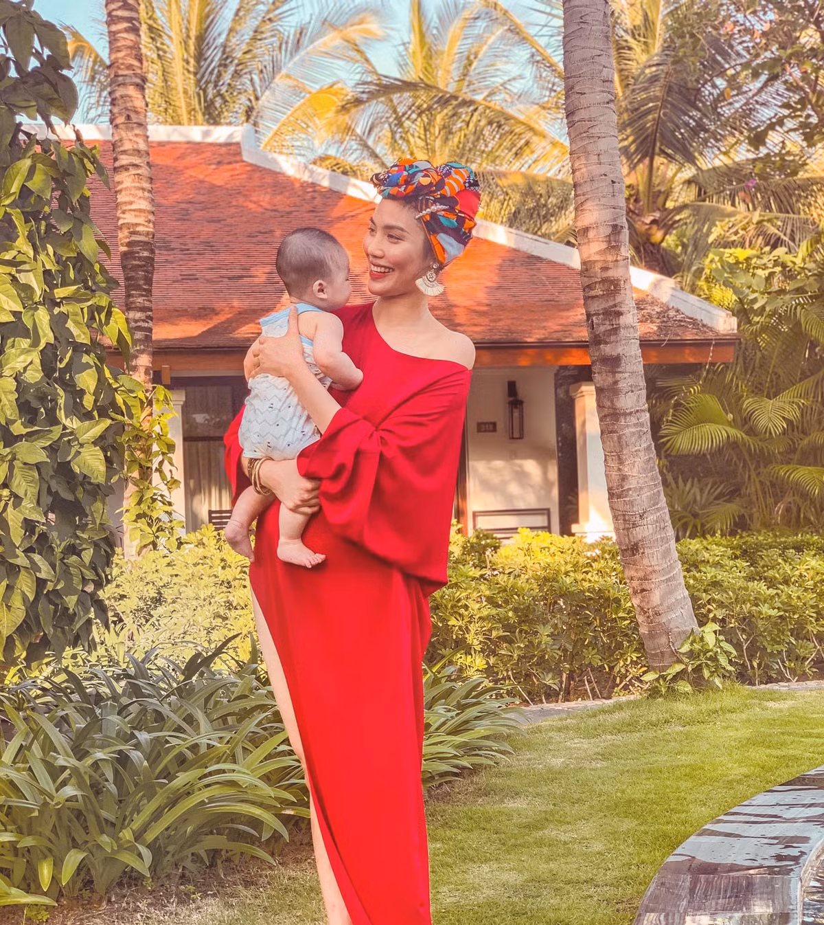 Người đẹp sinh năm 1992 lộ vai trần với đầm đỏ lệch vai trong chuyến du lịch cùng cậu con trai nhỏ.