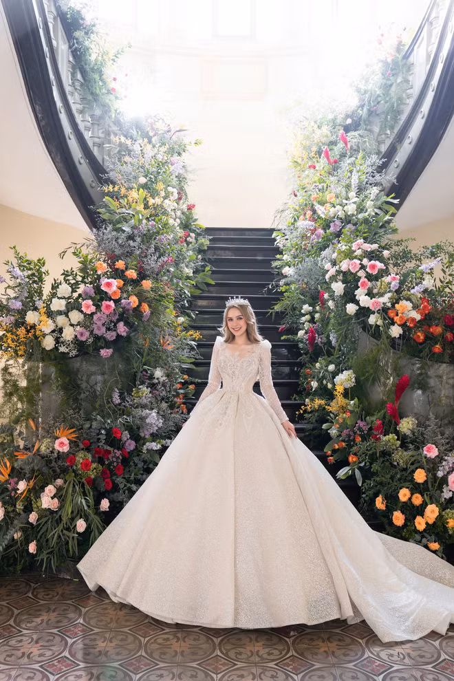 Với kỹ thuật xếp tầng độc đáo khéo léo trên chất vải Sparkle Organza được nhập khẩu từ Ý có màu Champagne lạ mắt, chiếc váy còn được đính kết theo họa tiết hoàng gia, kết hợp 30.000 viên đá Swarovski ánh bạc và pha lê ánh trắng.