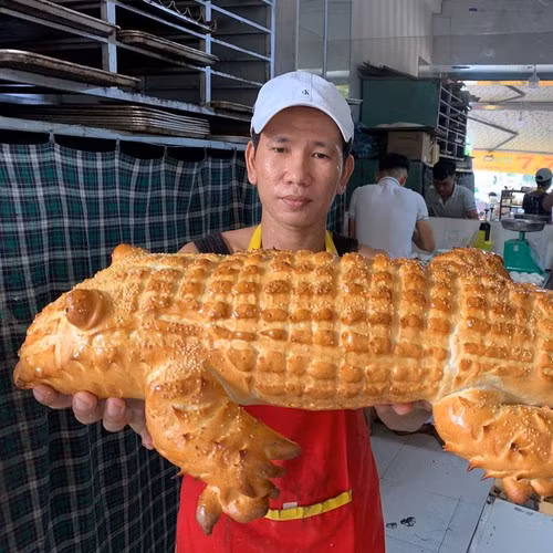 Không chỉ tạo hình độc đáo, chiếc bánh mì còn có kích thước "siêu to, khổng lồ" khiến nhiều người không khỏi tò mò về nguồn gốc của chiếc bánh. Đây là sáng tạo của cửa hàng “Lò bánh mì 7.7” ở Long Xuyên, An Giang.