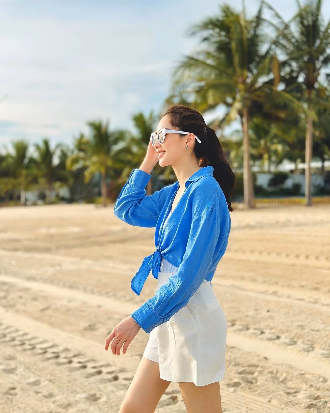Đôi khi thay đổi phong cách, Đặng Thu Thảo thả dáng trên bãi biển với trang phục phối hai gam màu trắng - xanh mát mắt. Bà mẹ hai con diện quần shorts tôn chân thon, kết hợp sơ mi thắt nơ ngang eo kín đáo.