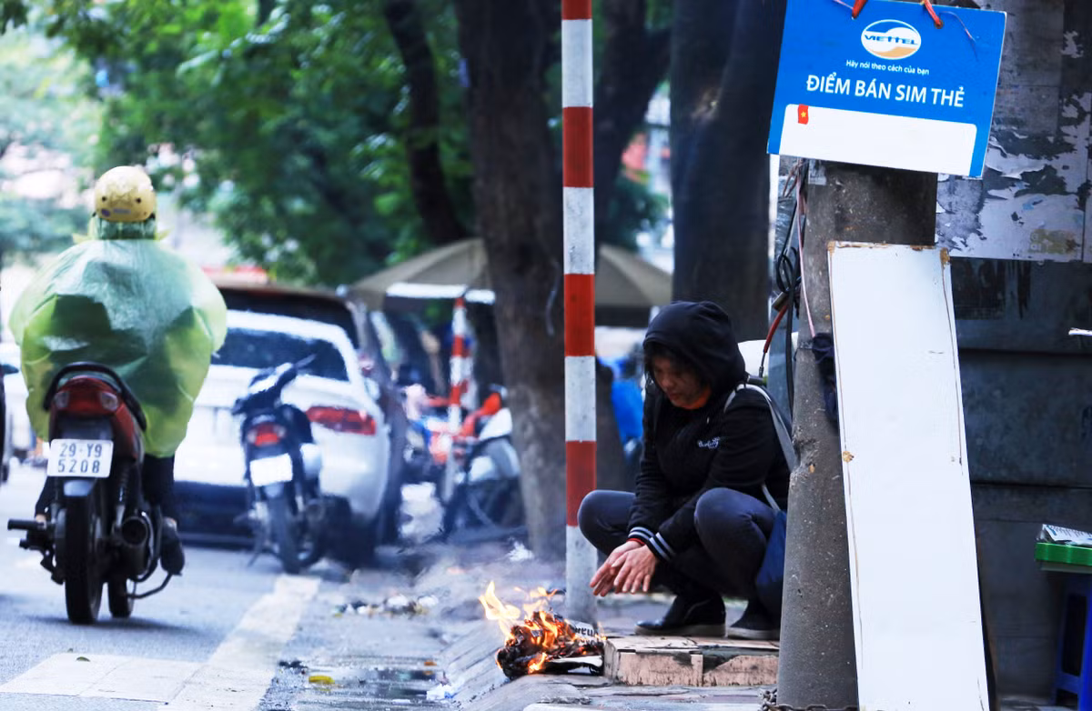 Trên đường Phan Đình Phùng, một người phụ nữ không có củi nên đành tạm đốt vài tờ giấy để hơ qua tay cho đỡ lạnh.