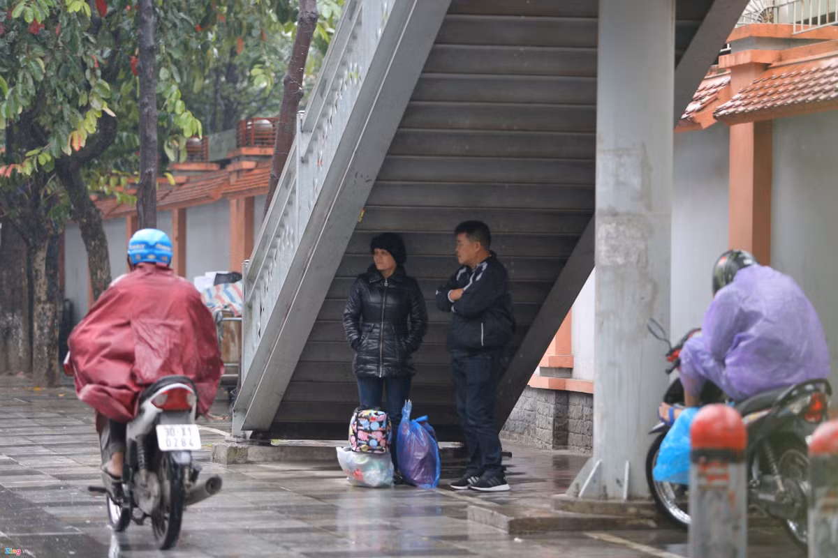 Nhiều người trú mưa và né gió dưới gầm cầu thang lên cầu vượt bộ hành
