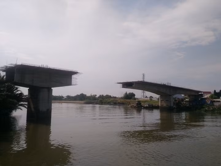 Tháng 6/2012, cầu mới chính thức được khởi công với gần 300 tỷ đồng và dự kiến xong sau 17 tháng. Nhưng đến nay, đã gần 10 năm trôi qua, cầu mới chỉ là hai khối nhịp dầm đúc hẫng nằm chơi vơi giữa rạch và bờ.