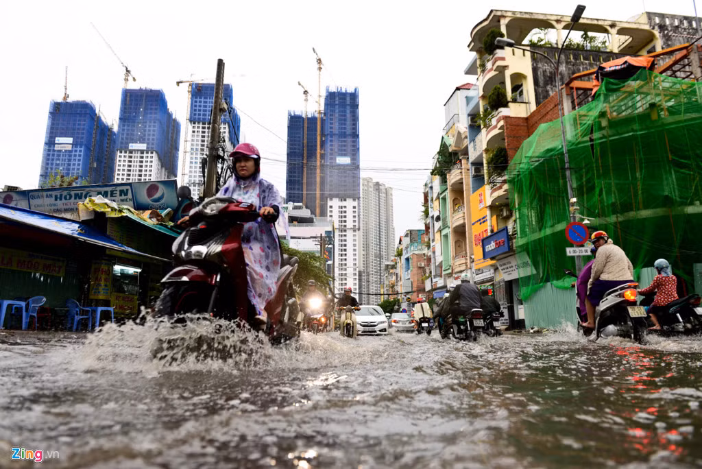 Phương tiện di chuyển khó khăn qua dòng nước ngập trong hẻm 602 Điện Biên Phủ. Con đường này dẫn ra đường Nguyễn Hữu Cảnh, một nơi thường xuyên bị ngập sau mưa.