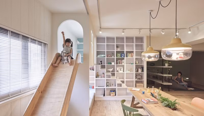 Tủ sách và máng trượt đặt trong cùng một không gian để bé vừa học lại có thể vừa chơi.