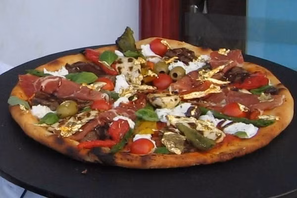 Pizza trứng cá muối Caviar sâm-panh và vàng vụn ở Rome, Ý: Nhân của chiếc bánh này bao gồm trứng cá muối ngâm rượu sâm-panh Dom Perignon, cá hồi hun khói Scotland, tôm hùm ướp trong cognac, thịt nai hảo hạng, thịt giăm bông prosciutto nổi tiếng và giấm lâu năm. Ở bước cuối cùng, nó còn được rắc thêm những lát vàng vụn 24k. Ảnh: Internet.