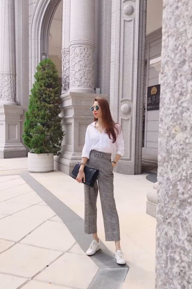 Cô kết hợp sơ mi trắng cùng quần xám cạp cao và giày thể thao trắng rất phong cách.