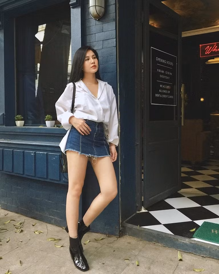 Áo sơ mi trắng và váy jean ngắn khoe đôi chân dài trắng nõn.