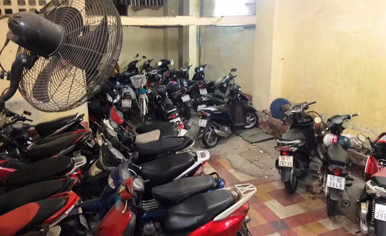 Ngay khi bước vào chung cư là khu vực để xe có diện tích nhỏ, vừa dùng để gửi xe cho cư dân và khách mua hàng, ăn uống cùng đồ đạc người buôn bán treo, đặt luộm thuộm.