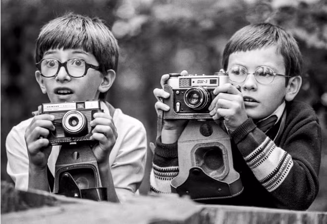 Hai em nhỏ cầm máy ảnh hồi thập niên 1980.