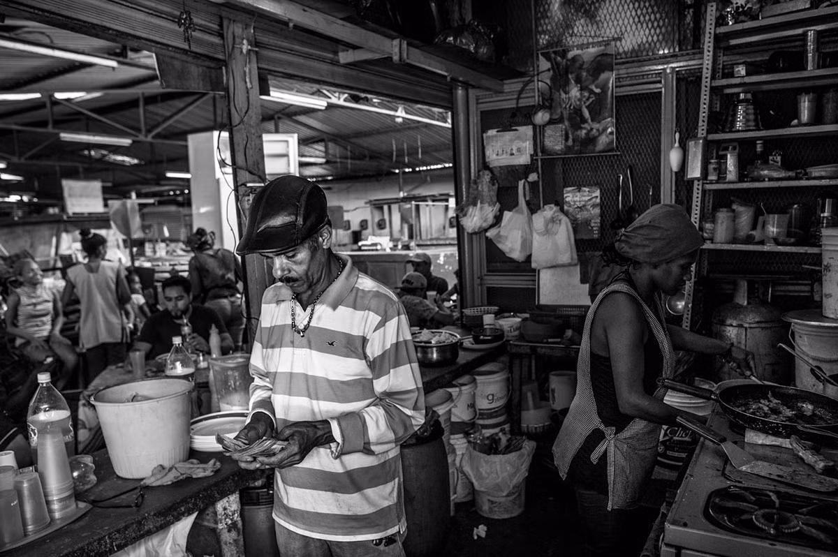 Chủ một quầy đồ ăn nhỏ trong chợ hoa quả đang đếm tiền.