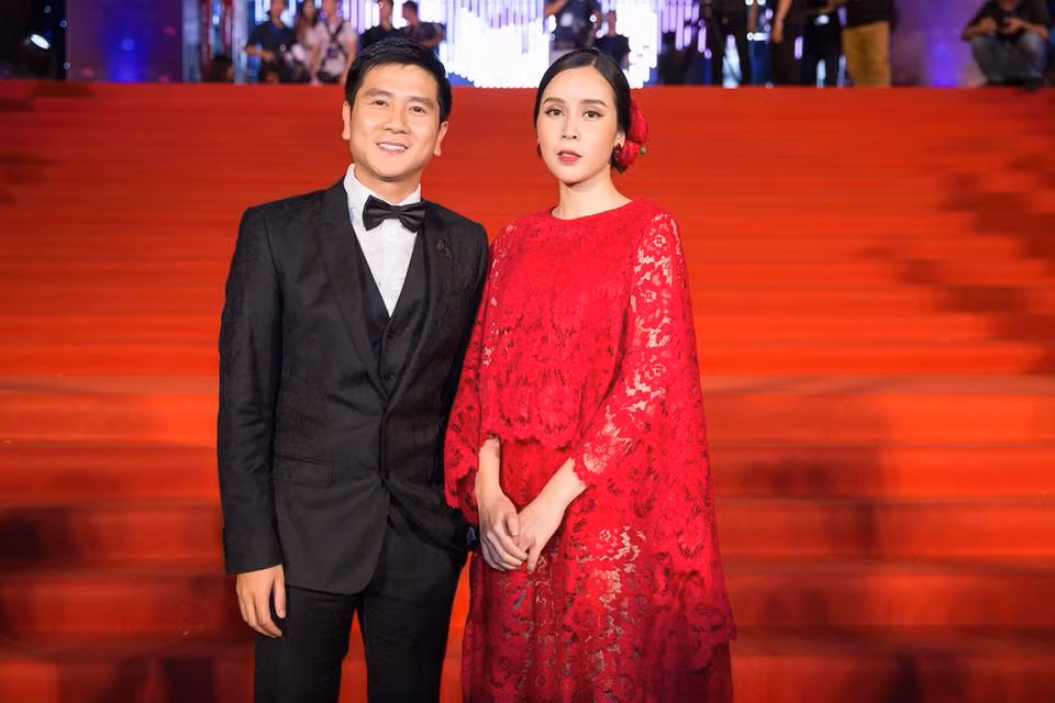 Hồ Hoài Anh lịch thiệp với vest đen, sánh bước bên Lưu Hương Giang lộng lẫy trong chiếc đầm đỏ nổi bật.