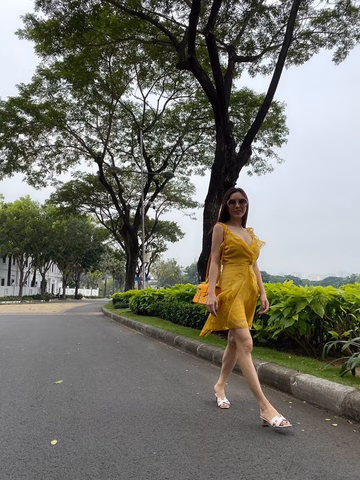 Hoa hậu sinh năm 1976 diện chiếc váy vàng gợi cảm phối thêm chiếc túi xách cùng tông sang chảnh.