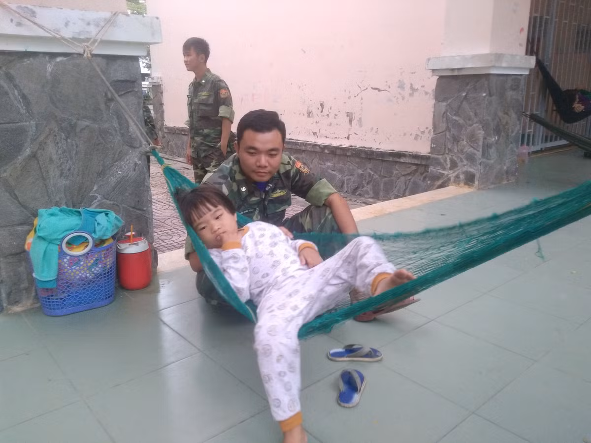Một chiến sĩ đang vui đùa cùng bé gái bên chiếc võng.