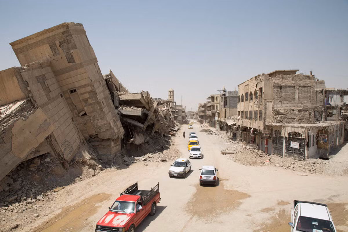 Hàng xe di chuyển giữa một con phố đổ nát ở Mosul mọi thứ được giữ nguyên như cách đây một năm. Ảnh: aljazeera.