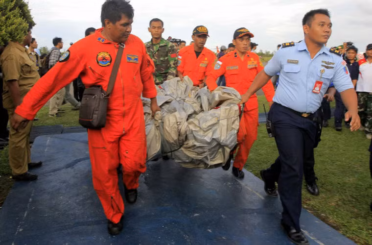 Thành viên Không quân Indonesia mang theo vật thể được cho là từ cửa thoát hiểm của chiếc máy bay mất tích.