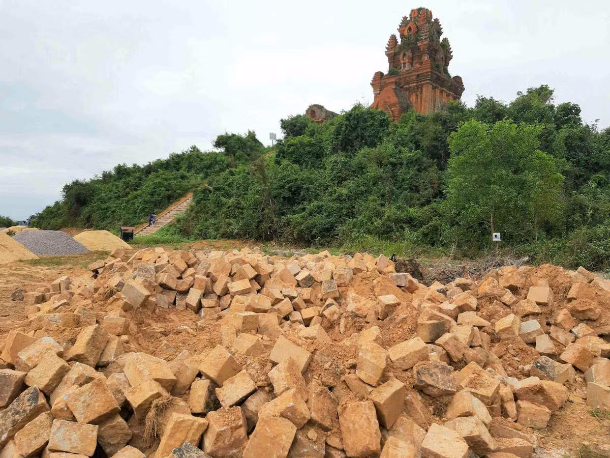 Trong quá trình thi công xây dựng, tu bổ, tôn tạo di tích Tháp Bánh Ít, chủ đầu tư và nhà thầu thi công phải dùng thủ công, máy đầm đất cầm tay san gạt sân phía trước tháp chính thì lại đưa xe cơ giới máy múc vào “oanh tạc” di tích, không đúng hồ sơ thiết kế được thẩm định.(Ảnh: Tài nguyên và Môi trường).