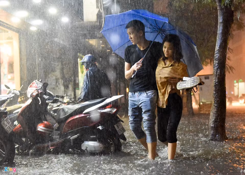 Đoạn ngã tư Thái Hà - Tây Sơn, nước ngập lên vỉa hè, đôi bạn trẻ phải cởi giày lội.