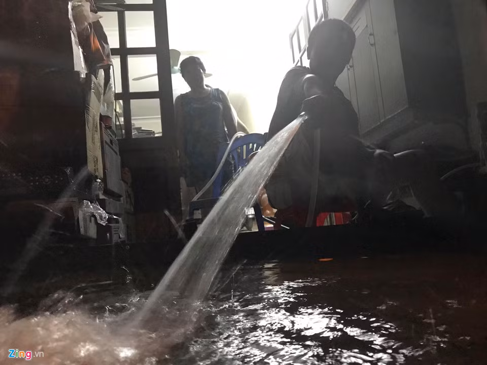 Người dân dùng máy bơm hút nước ra khỏi nhà mình trên phố Hoa Bằng, quận Cầu Giấy lúc 21h.