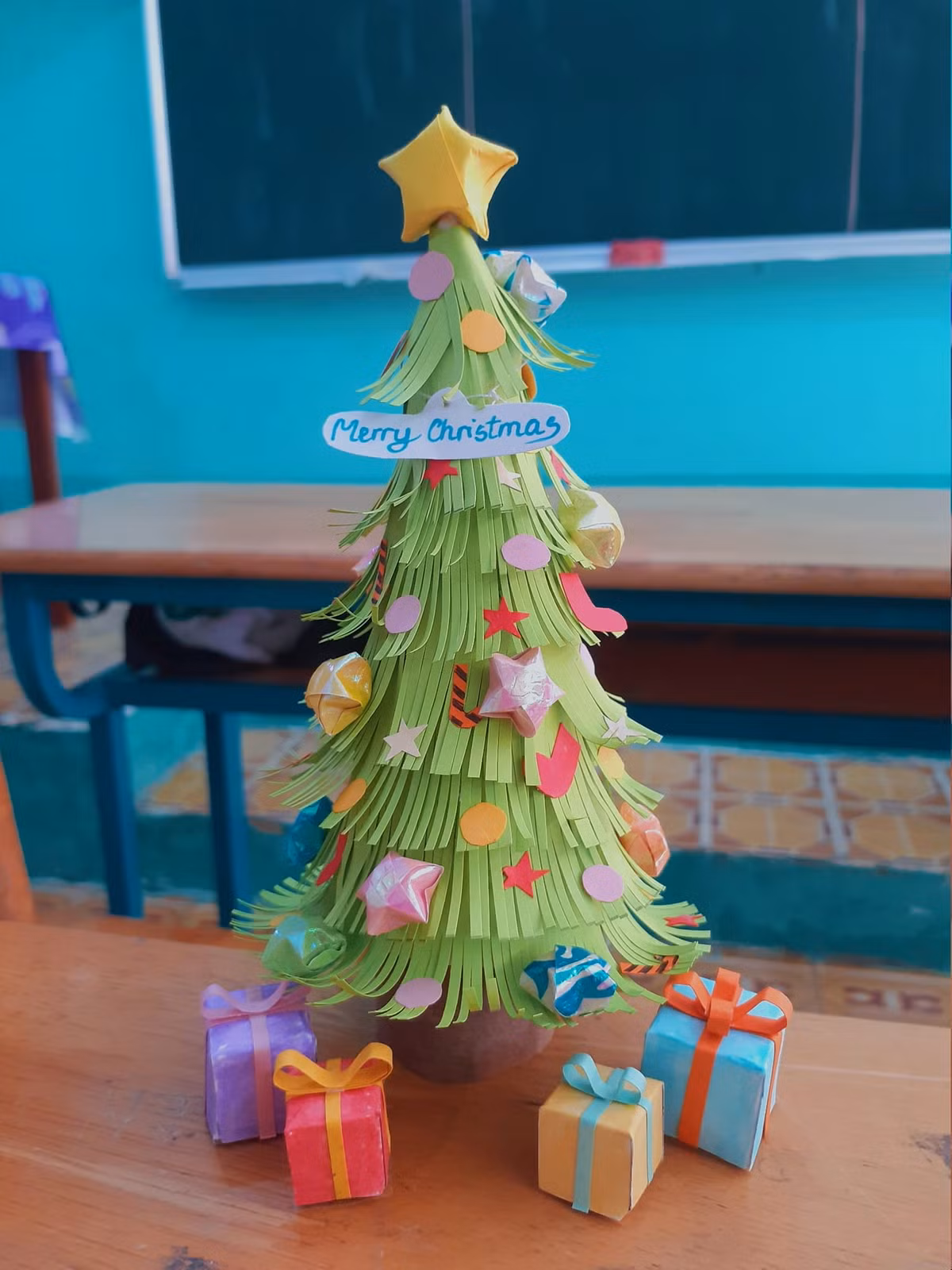 Chỉ với những nguyên vật liệu đơn giản như giấy màu, băng dính, keo dán, các em đã tạo hình cây thông nhỏ nhắn với chiều cao khoảng vài gang tay.