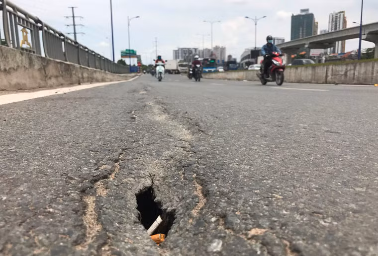 Xung quanh các lỗ thủng là vết nứt của mặt đường nhựa, kéo dài nhiều mét chi chít trên mặt cầu.