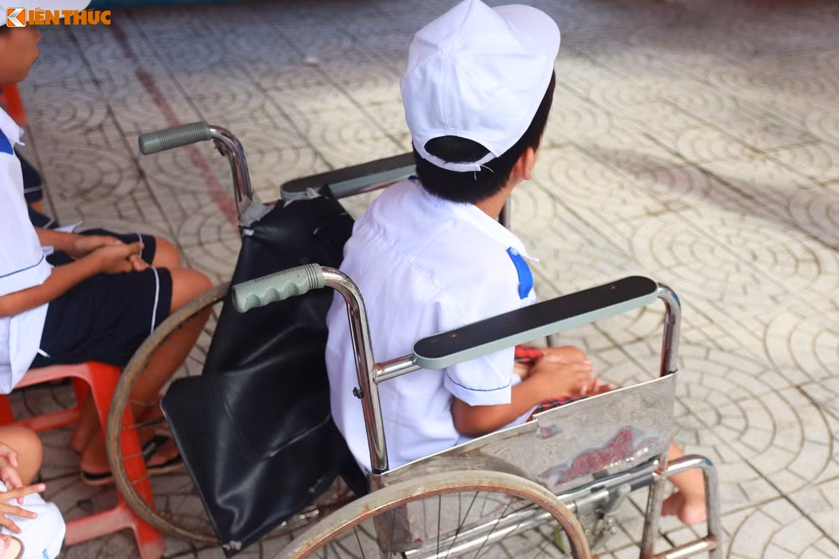 Một trẻ em khuyết tật phải ngồi trên chiếc xe lăn không lành lặn. Ảnh: Quốc Minh.