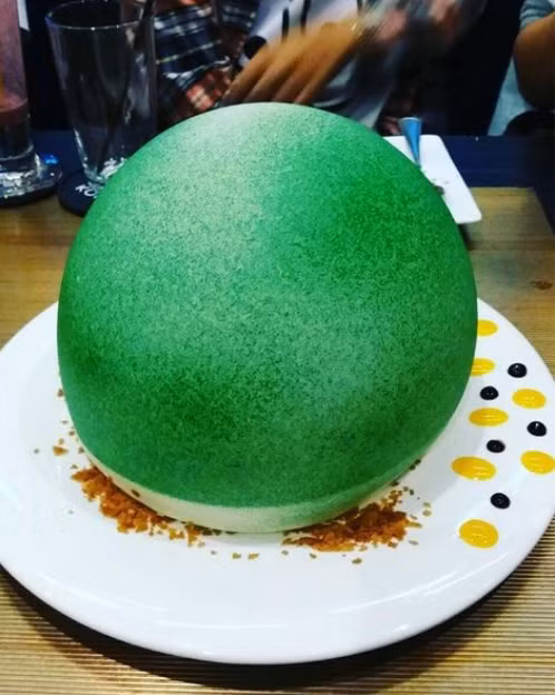 Muốn biết bên trong món ăn xanh mướt có tên “trái đất nóng lên” này là gì thì ngoài đợi 15 phút món ăn mới tới bàn thì khi ăn, bạn phải đợi người ta rưới lên một ít rượu contreau để lớp socola trắng hình cầu kia tan ra và sụp xuống. Thường thì “nội thất” bên trong là sandwich kẹp kem, kẹo dẻo nướng và salad trái cây. (Nguồn ảnh: WOB)