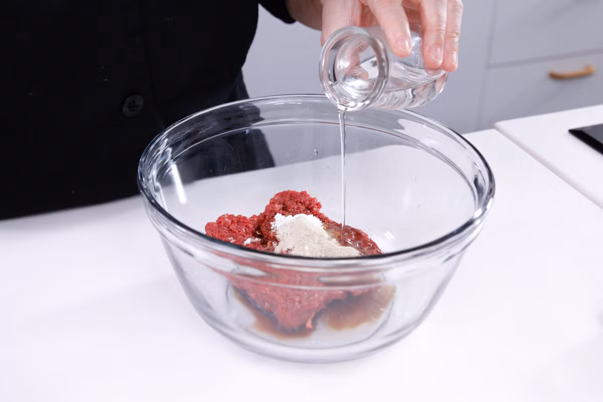 Cho thịt bò, nước tương, bột bắp, đường, hạt tiêu và nước vào trộn đều. Có thể cho thêm một chút rượu nấu cho thơm. 