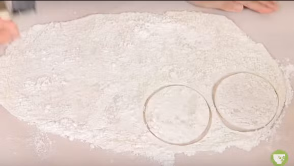 Để cán bột thành vỏ bánh mochi, rắc một ít bột bắp hoặc bột khoai tây lên giấy rồi đổ bột nếp lên, dùng cây cán bột cán mỏng đều rồi cho vào tủ lạnh 30 phút. Tiếp đó cùng khuôn cắt vỏ bánh thành những vòng tròn đều như thế này, đường kính khoảng 8cm và tùy thuộc vào độ lớn của nhân kem.