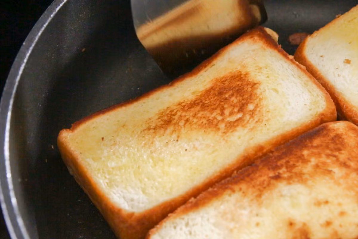 Bắc chảo lên bếp, cho một ít bơ vào rồi cho bánh mì vào nướng. Lưu ý không để lửa quá to để bánh mì khỏi bị cháy. Khi hai mặt bánh mì hơi xém màu nâu vàng là được.