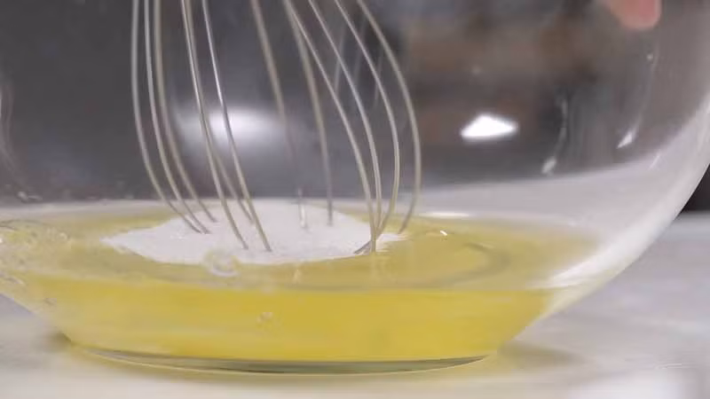 Để làm phần cốt bánh ngọt, lấy 90g lòng trắng trứng đánh với đường cho đến khi nổi bọt mềm. Tiếp đó lấy một chiếc rây rồi đổ lần lượt bột hạnh nhân, bột đường, bột làm bánh, bột ca cao vào và đánh đều.