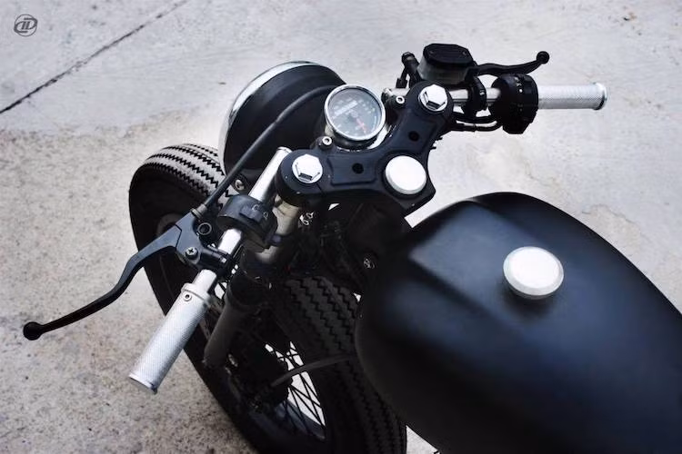 Theo đúng phong cách cafe racer tối giản, chiếc xe đã được trang bị cặp tay lái clip-on đặt thấp và một đồng hồ tốc độ Kege ở giữa chảng ba. Một nét đặc trưng của những bản độ từ DDD là các chi tiết như bao tay, dàn để chân, nắp xăng... bằng nhôm phay vẫn tiếp tục xuất hiện trên bản độ này.