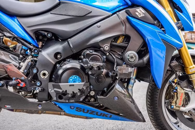Động cơ nguyên bản của GSX-S1000 đã được độ nhẹ lại phần xăng gió nhờ lọc gió BMC, bộ ECU piggyback Power Commander 5 Autotune tự chỉnh map, cổ pô Akrapovic full titan kèm van pô. Hai bên động cơ được bảo vệ bởi cặp ốp chống đổ của T-Rex được làm từ nhôm CNC.