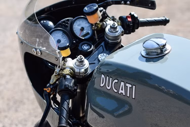 Dù là một mẫu sport touring nhưng cụm ghi-đông clip-on nguyên bản của 1000SS vốn đã khá thể thao, chính vì vậy Redmax Speedshop đã giữ nguyên chi tiết này, cùng với bảng đồng hồ của chiếc xe. Trong khi đó, xưởng độ đã gò bình xăng lớn của 1000SS theo mẫu của 750SS, kèm theo nắp xăng với kiểu dáng cổ điển.