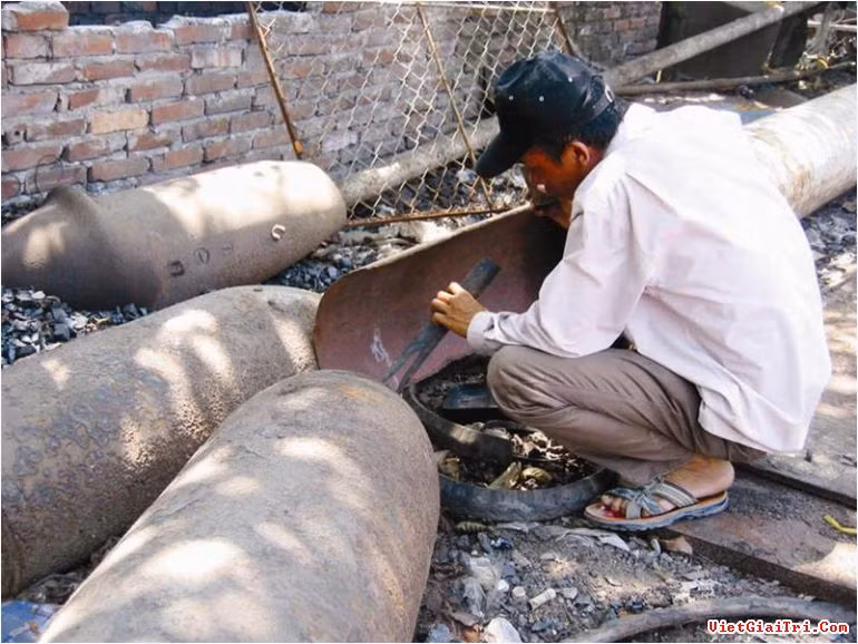 Theo một con số thống kê, có hơn 15 triệu tấn bom, đạn từng được rải xuống Việt Nam, trong đó có 800 ngàn tấn vẫn xót lại cho đến tận hôm nay. Có hàng ngàn người là nạn nhân của bom mìn và một nửa trong số đó đã vĩnh viễn trở thành người thiên cổ. Ảnh: Một người đàn ông đang đục vào một quả bom lớn nhằm phá lấy vỏ. Nguồn: Tuổi Trẻ