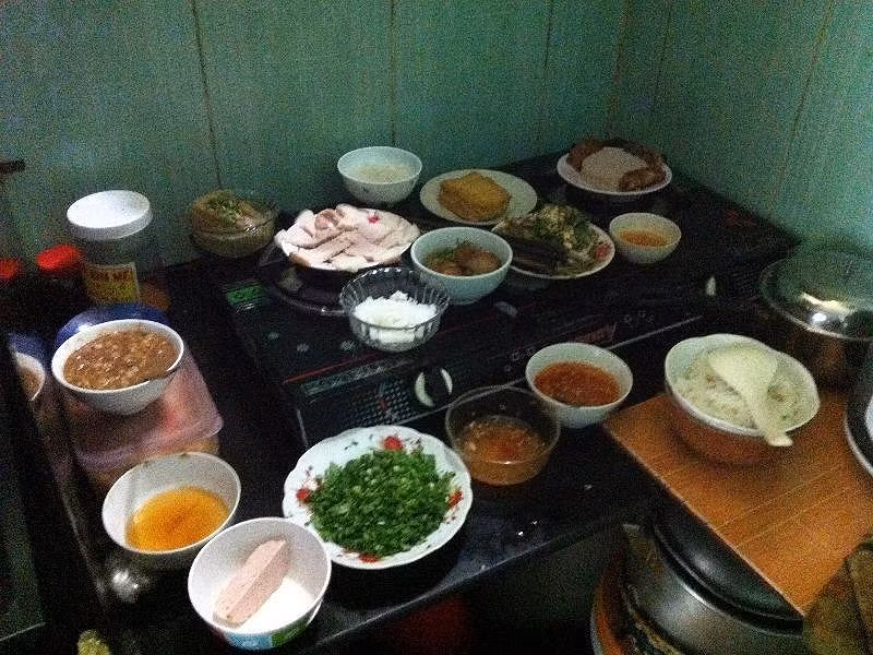 Ngày nay mọi người cũng cúng mâm cơm mặn gồm thịt, cá lóc nướng, bánh chưng, bánh tét... đặt ngay trên bếp. Ảnh: NT
