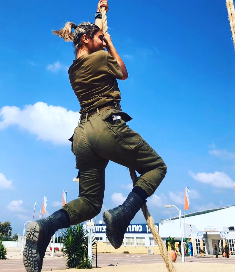Vóc dáng hầm hố nhưng không kém phần gợi cảm của một nữ quân nhân Israel trong quá trình tập đu dây trên thao trường.