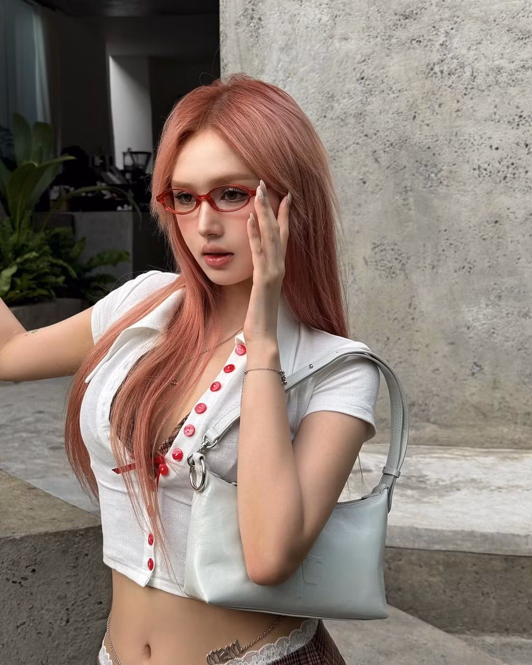 Nàng hot girl hoàn thiện set đồ với chiếc kính oval màu đỏ đậm hơi thở Y2K.
