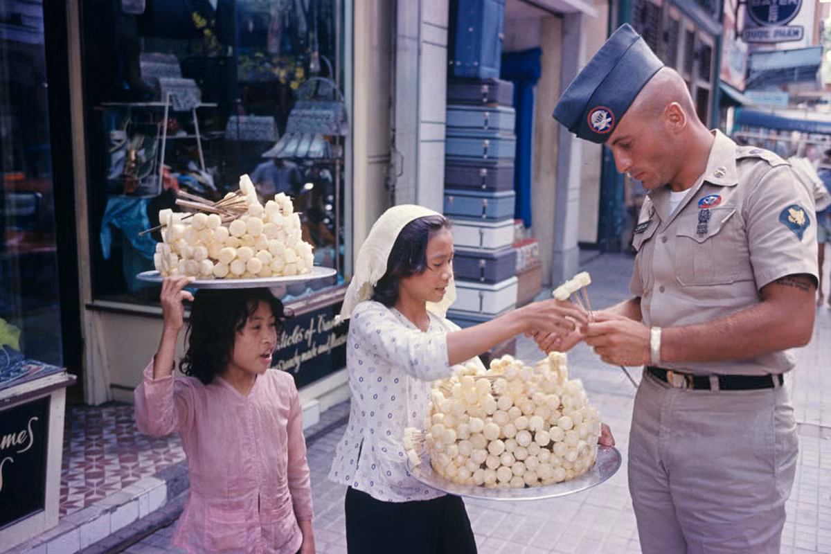Hai bé gái bán mía ghim cho một sĩ quan Mỹ trên đường phố Sài Gòn, 1965. Ảnh: Jean-Claude Sauer.