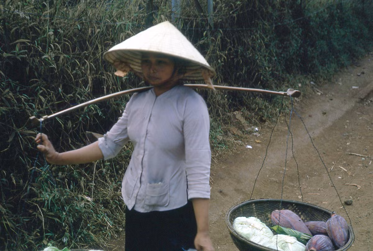 Người phụ nữ gánh cải bắp và hoa chuối ra chợ bán. Ảnh: Donald MacKinnon.