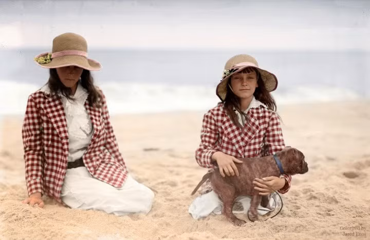 Hai cô bé Jean và Charlotte Potter ngồi ở bãi biển với chó cưng, khoảng năm 1910 -1 915. Ảnh: Imgur.