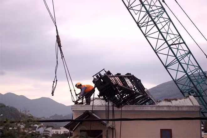 Đơn vị thi công kéo chiếc cần cẩu bị gãy khỏi nhà dân. Nguồn ảnh: Công an nhân dân.