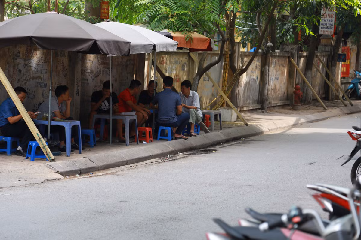 Cả người bán nước và khách đang coi thường tính mạng của bản thân khi ngồi dưới bức tường sắp đổ.
